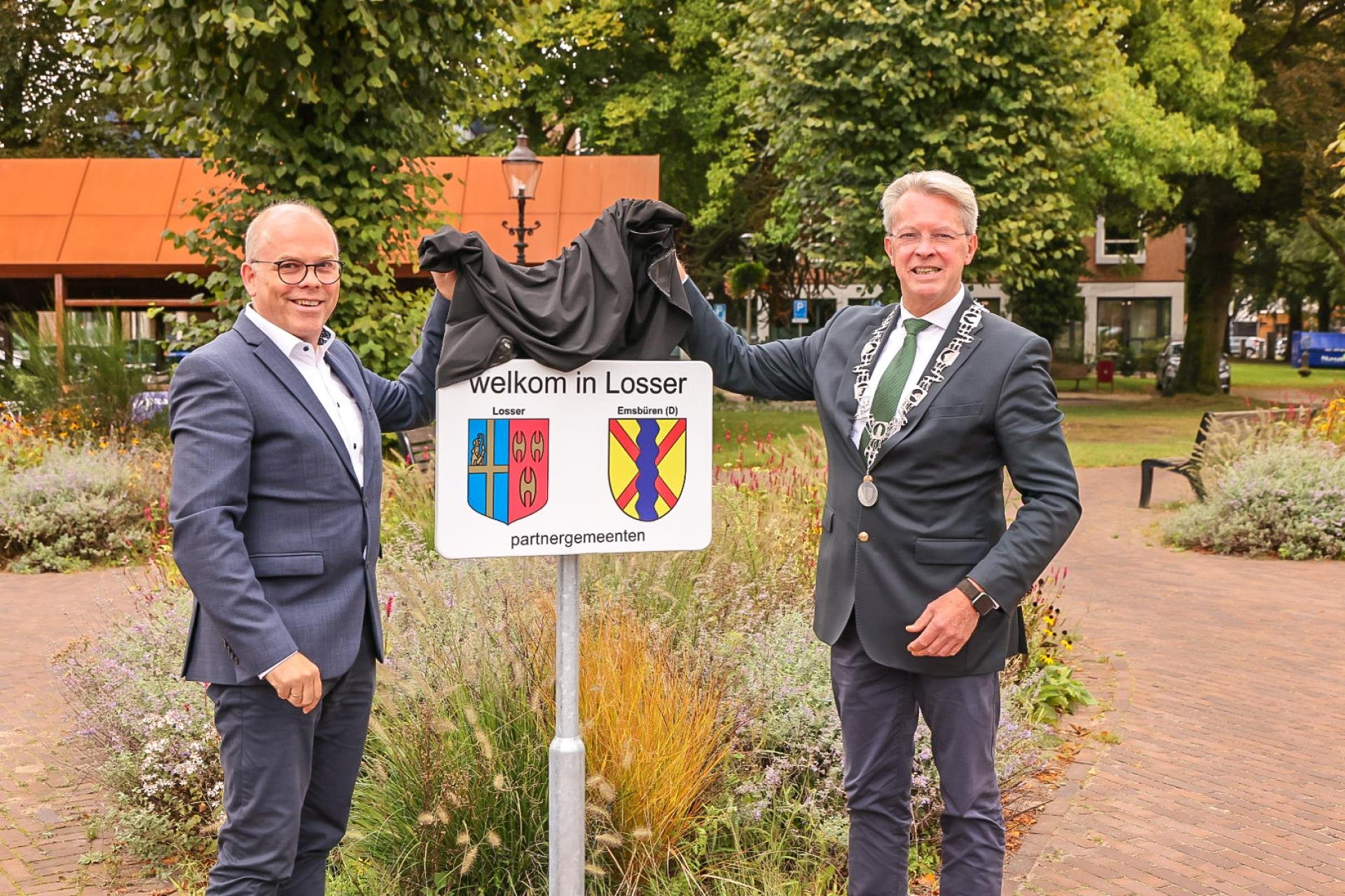 Burgermeesters van Emsbüren en Losser bij het onthulde bord met de wapens van beide gemeenten