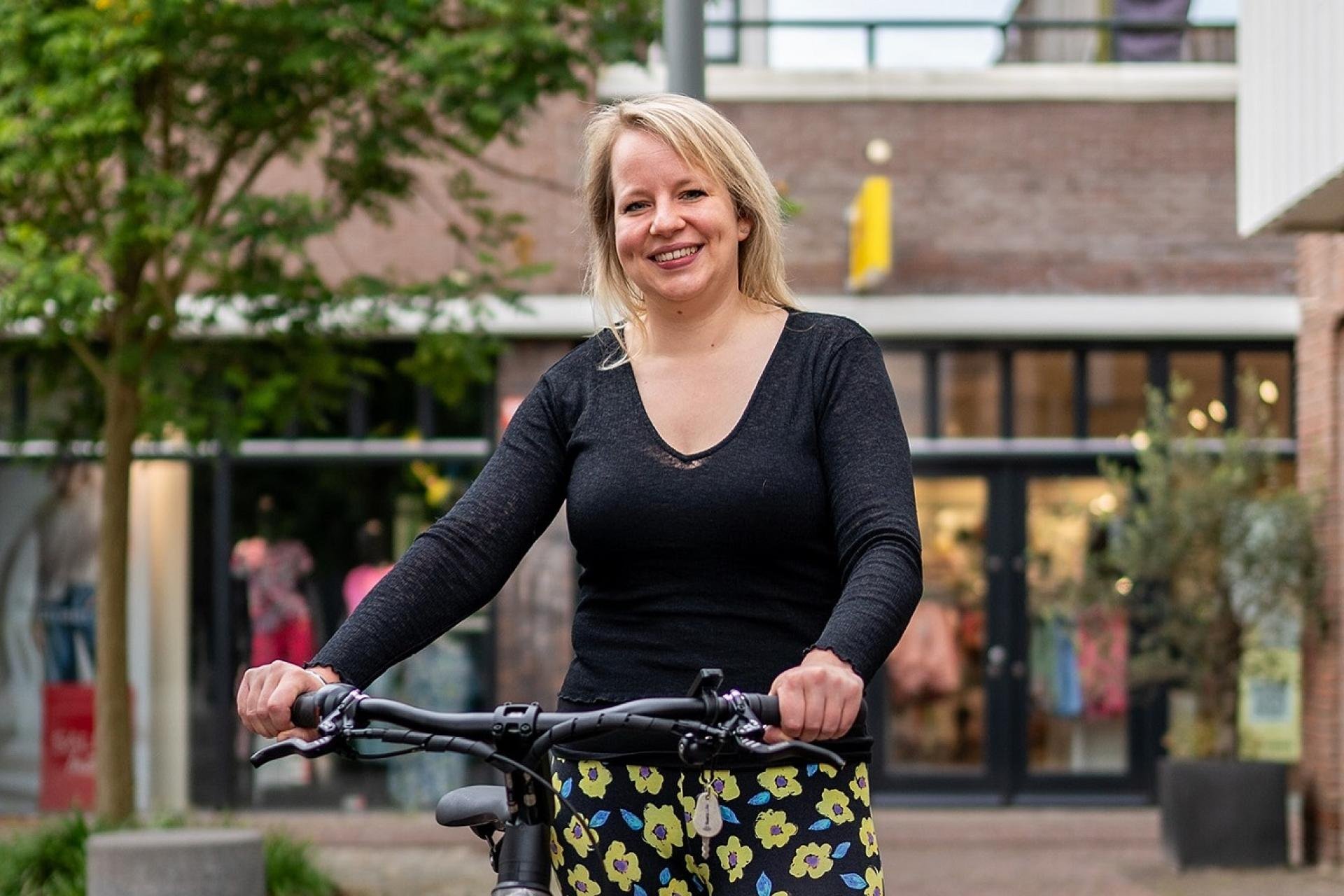 vrouw naast de fiets bij winkelcentrum