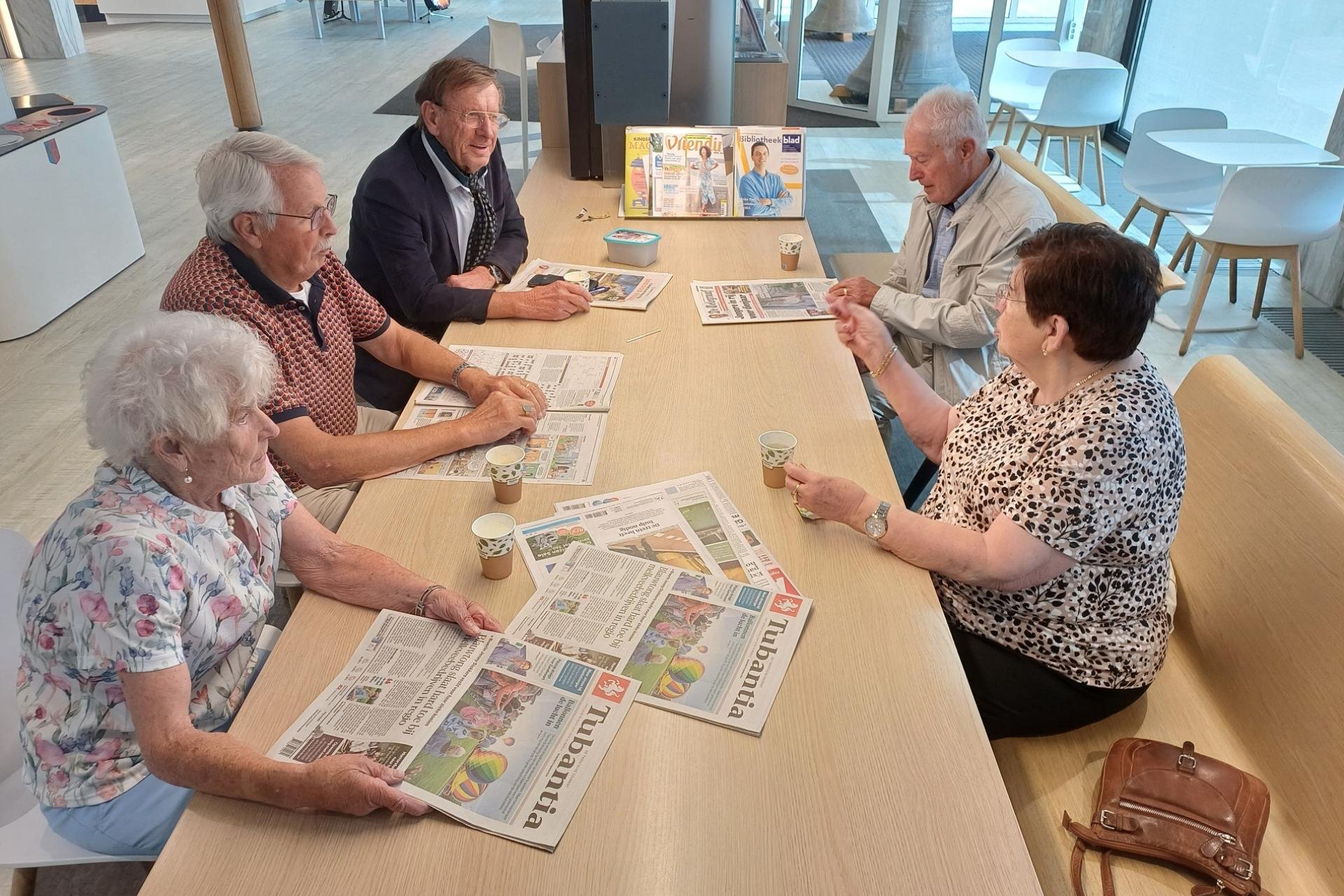 mensen rond een tafel met een krant